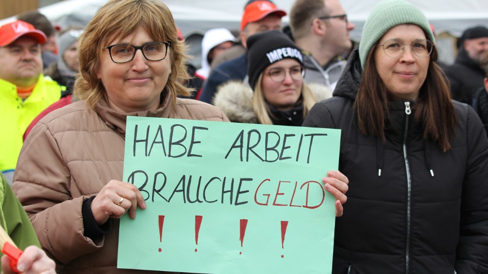 Eine Mitarbeiterin der Firma Schabmüller hält beim Streik ein Schild mit der Aufschrift "Habe Arbeit, brauche Geld".