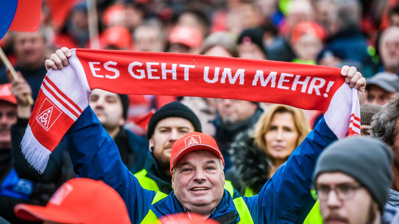 Mann in einer Menschenmenge hält einen Schal mit der Aufschrift 