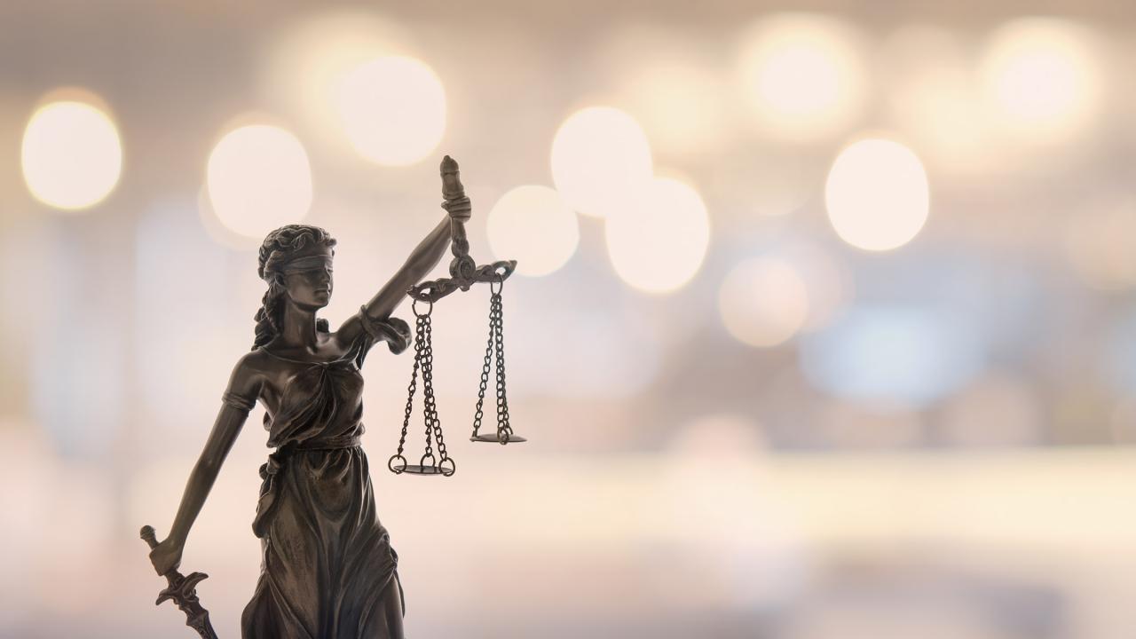 Justitia, die Göttin der Gerechtigkeit vor unscharfen Hintergrund