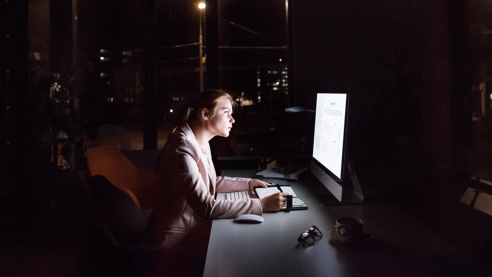 Geschäftsfrau vor Computer-Bildschirm im Büro in der Nacht