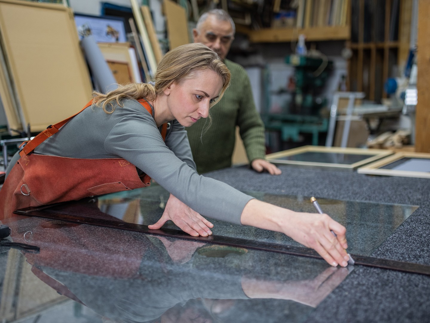 Eine Glaserin schneidet in der Werkstatt Glas zu