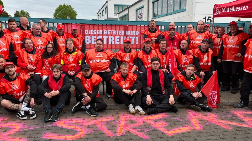Gruppenfoto von Beschäftigten von Stanley Feinwerktechnik in Lahnau (Mittelhessen) in roten Streikwesten am zweiten Streiktag.
