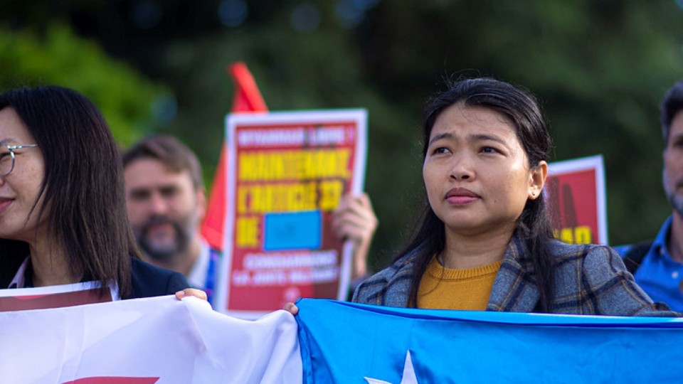 Khaing Zar, Gewerkschafterin aus Myanmar, bei einer Demo in Genf mit einer Fahne.