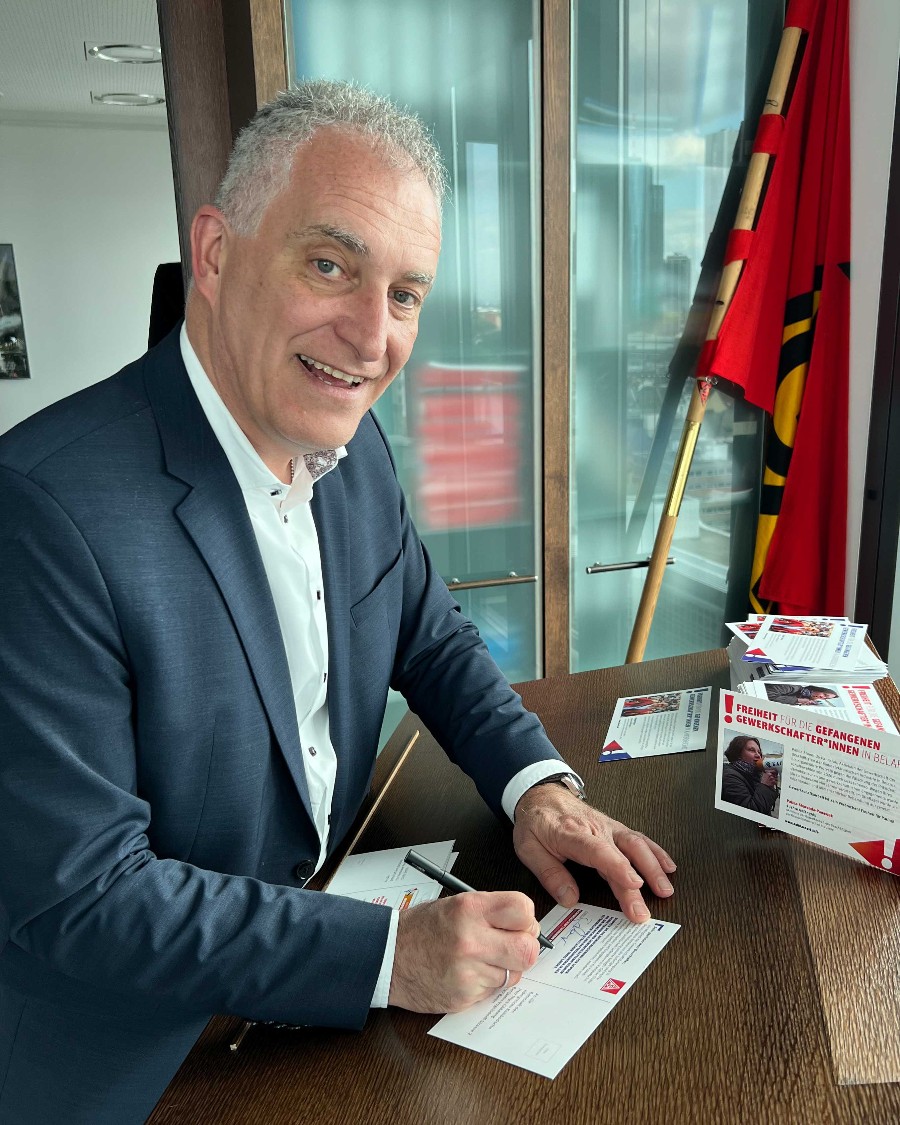 Jürgen Kerner unterschreibt eine Postkarte, in der die Freilassung inhaftierter Gewerkschafter gefordert wird